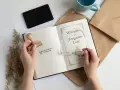 Ręce trzymają stempel z napisem "Biblioteczka Aleksandry" i książkę "Whispers of the Forgotten Lore". To idealny zestaw do tworzenia własnego exlibrisu.