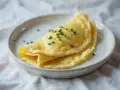 Złocisty, delikatny omlet francuski, posypany szczypiorkiem. Idealny przykład, jak zrobić francuski omlet.