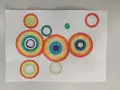 Kolorowa abstrakcja z koncentrycznymi okręgami przypominającymi tęczę.