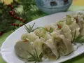 Pyszne pierogi ukraińskie, udekorowane szczypiorkiem i rozmarynem, prezentują się apetycznie na białym talerzu.
