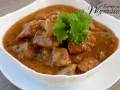 Aromaticzny gulasz z karkówki w sosie własnym, udekorowany gałązką natki pietruszki. Idealny na sycący obiad.