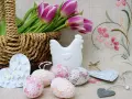Wielkanocne dekoracje: koszyk z tulipanami, ceramiczna kurka, ozdobne jajka i serca.