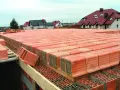 Budowa stropu ackermana. Czerwone pustaki ceramiczne ułożone w rzędach, tworzące solidną konstrukcję.