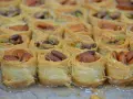 Słodkie gniazdka z cienkiego ciasta filo, wypełnione migdałami i pistacjami, błyszczą od syropu.