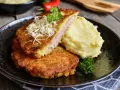 Złocisty kotlet po parysku, nadziany szynką i serem, podany z purée ziemniaczanym i natką pietruszki. Pyszne danie na obiad.