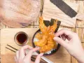 Ręce układają chrupiące krewetki tempura na ryżu. Idealny przepis na tempurę do domowego obiadu.