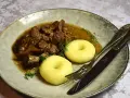 Gulasz z dzika z kluskami śląskimi, ozdobiony koperkiem. Aromatyczne danie, które rozpływa się w ustach.