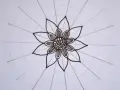 Kwiatowa mandala, rysowana czarnym tuszem, z delikatnymi okręgami i promieniami.