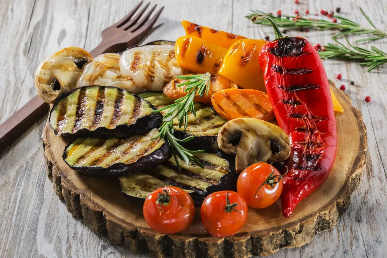 Pyszne jedzenie na grilla: grillowany bakłażan, papryka, pieczarki, pomidorki i marchewka, udekorowane rozmarynem.