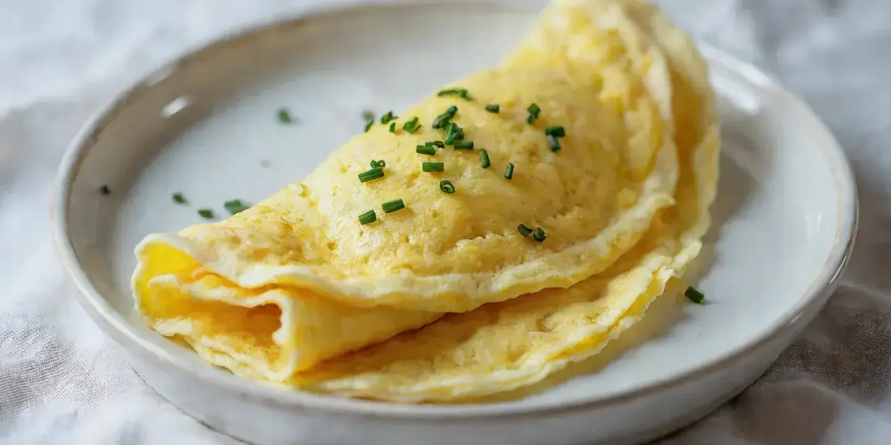 Złocisty, delikatny omlet francuski, posypany szczypiorkiem. Idealny przykład, jak zrobić francuski omlet.