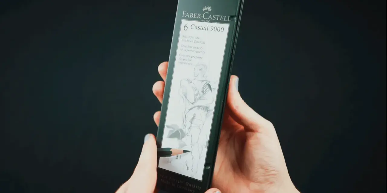 Dłonie trzymają opakowanie z sześcioma ołówkami Faber-Castell 9000. Jeden ołówek rysuje szkic postaci.