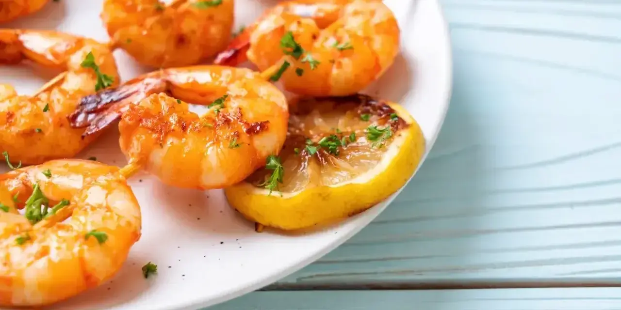 Soczyste krewetki z airfryer, podane z plasterkiem cytryny i posypane natką pietruszki. Idealne na szybką przekąskę.