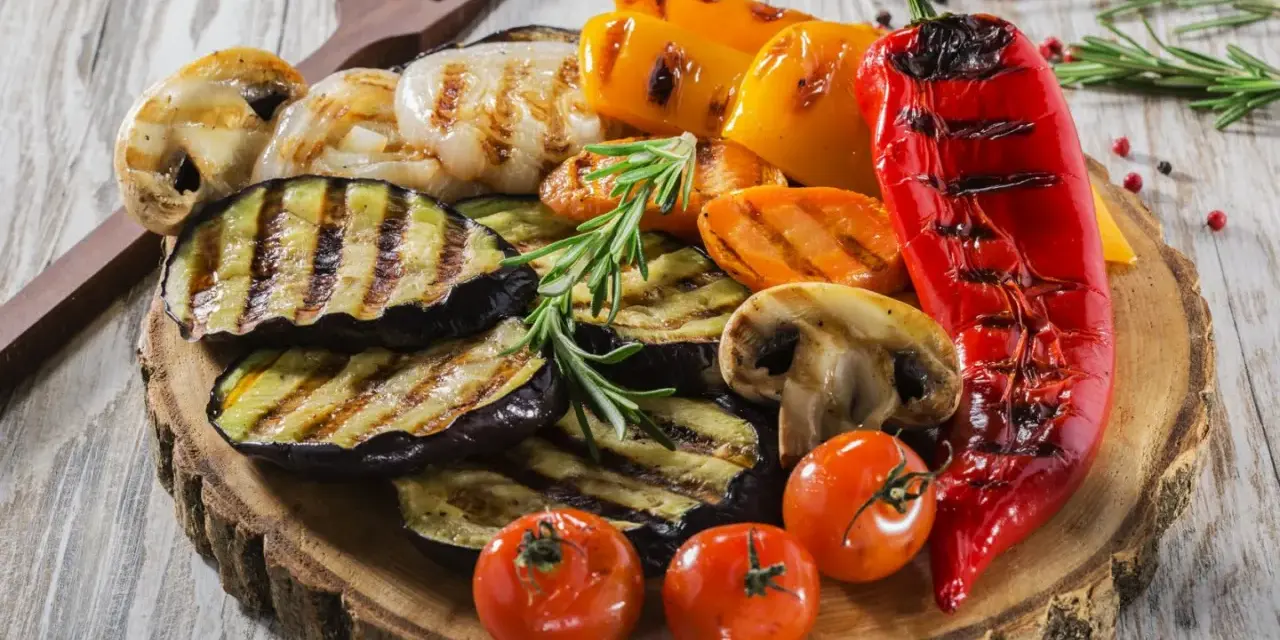 Pyszne jedzenie na grilla: grillowany bakłażan, papryka, pieczarki, pomidorki i marchewka, udekorowane rozmarynem.