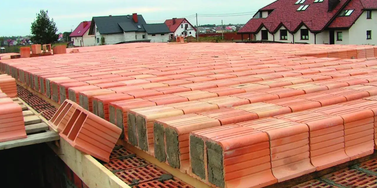 Budowa stropu ackermana. Czerwone pustaki ceramiczne ułożone w rzędach, tworzące solidną konstrukcję.