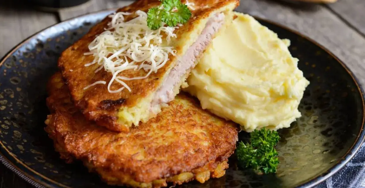 Złocisty kotlet po parysku, nadziany szynką i serem, podany z purée ziemniaczanym i natką pietruszki. Pyszne danie na obiad.