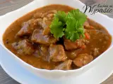 Aromaticzny gulasz z karkówki w sosie własnym, udekorowany gałązką natki pietruszki. Idealny na sycący obiad.