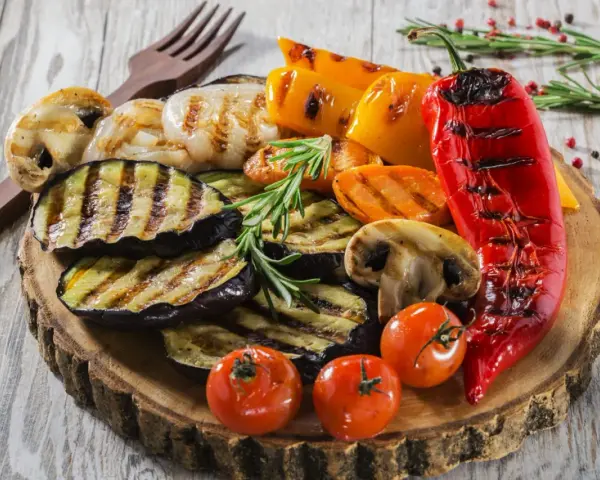 Pyszne jedzenie na grilla: grillowany bakłażan, papryka, pieczarki, pomidorki i marchewka, udekorowane rozmarynem.