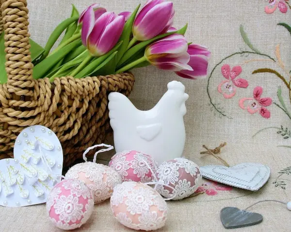 Wielkanocne dekoracje: koszyk z tulipanami, ceramiczna kurka, ozdobne jajka i serca.