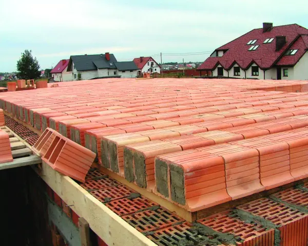 Budowa stropu ackermana. Czerwone pustaki ceramiczne ułożone w rzędach, tworzące solidną konstrukcję.