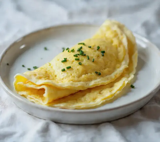 Złocisty, delikatny omlet francuski, posypany szczypiorkiem. Idealny przykład, jak zrobić francuski omlet.