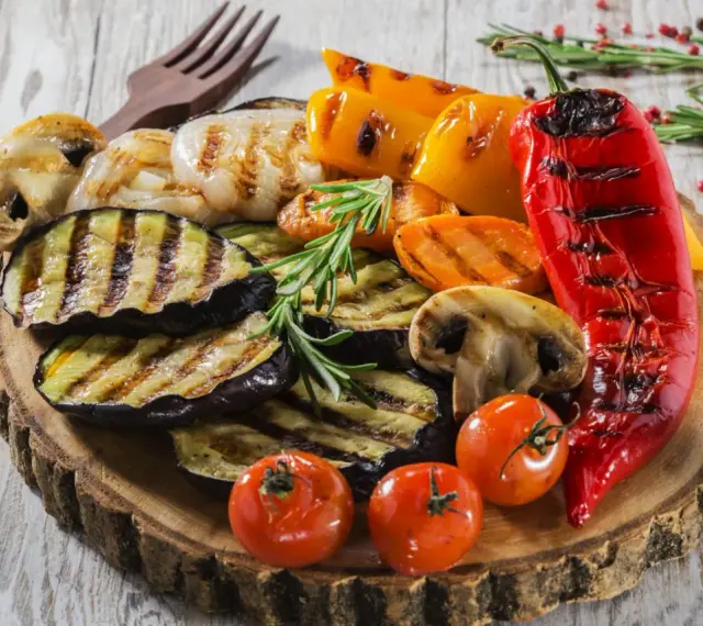Pyszne jedzenie na grilla: grillowany bakłażan, papryka, pieczarki, pomidorki i marchewka, udekorowane rozmarynem.