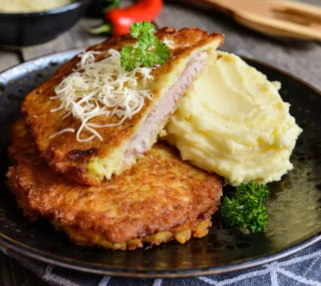 Złocisty kotlet po parysku, nadziany szynką i serem, podany z purée ziemniaczanym i natką pietruszki. Pyszne danie na obiad.