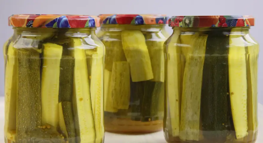 Słoiki z cukinią w zalewie słodko-kwaśnej z curry. Aromatyczne plastry cukinii, idealne na przetwory.