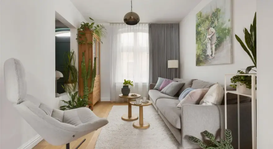Przytulny salon inspiracje: szara kanapa, fotel, drewniana komoda i mnóstwo zielonych roślin tworzą relaksującą atmosferę.
