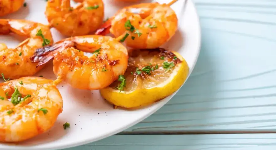 Soczyste krewetki z airfryer, podane z plasterkiem cytryny i posypane natką pietruszki. Idealne na szybką przekąskę.