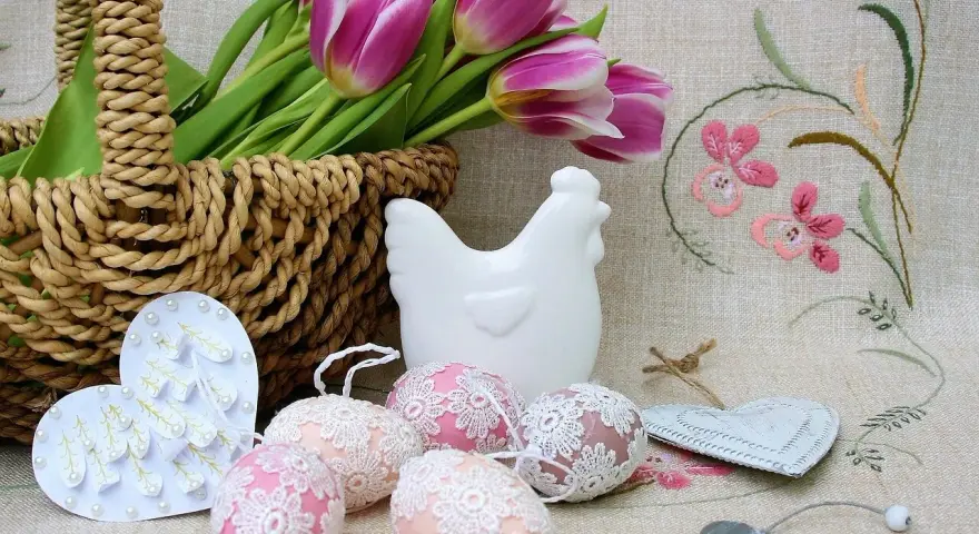 Wielkanocne dekoracje: koszyk z tulipanami, ceramiczna kurka, ozdobne jajka i serca.