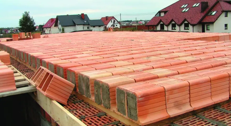 Budowa stropu ackermana. Czerwone pustaki ceramiczne ułożone w rzędach, tworzące solidną konstrukcję.