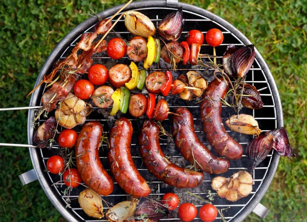 Pyszne jedzenie na grilla: kiełbaski, szaszłyki z boczkiem, pomidorki, papryka i cebula pieczone na ruszcie.