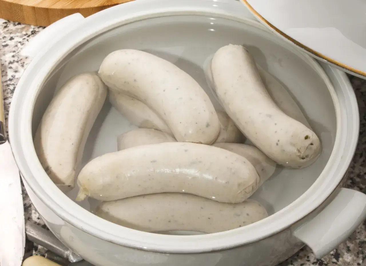 Kilka białych kiełbasek parzonych w garnku, gotowych do podania.
