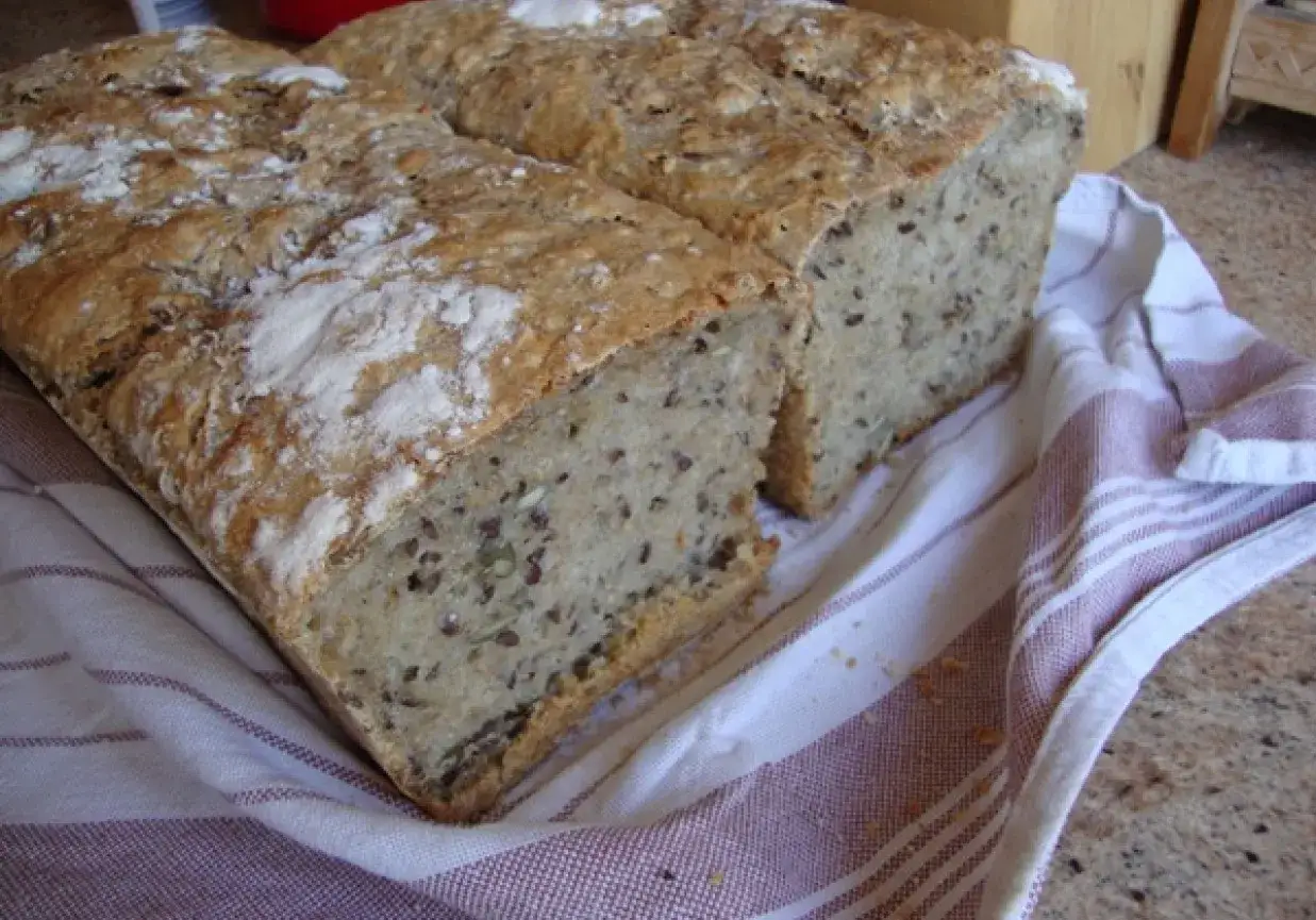 Dwa bochenki domowego chleba na zakwasie, z ziarnami, na lnianym ręczniku. Idealne, by zacząć przygodę, jak zrobić zakwas na chleb.