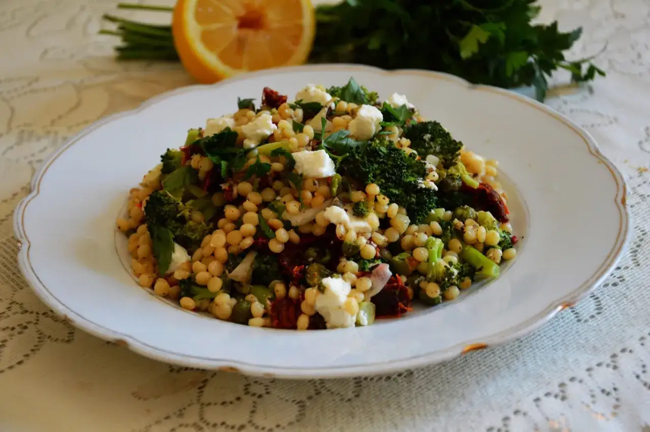 Pyszna kasza kuskus perłowa z brokułami, suszonymi pomidorami i fetą. Idealna na lekki posiłek.