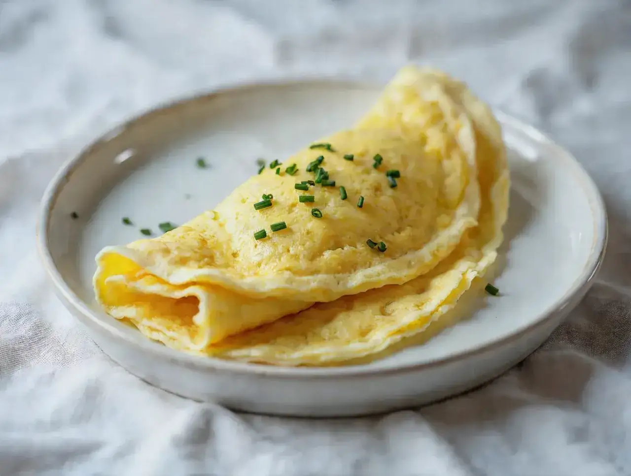 Złocisty, delikatny omlet francuski, posypany szczypiorkiem. Idealny przykład, jak zrobić francuski omlet.
